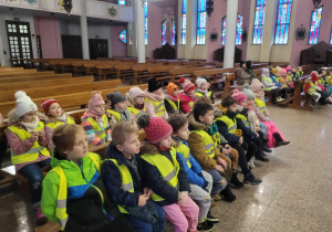 Dzieci siedzą na ławkach w kościele