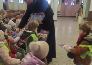 Dzieci otrzymują książki ze świątecznymi zadaniami