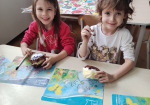 Lucynka i Anielka siedzą przy stoliku, malują farbami