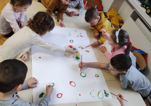 Dzieci na arkuszu papieru malują farbami kropki, koła