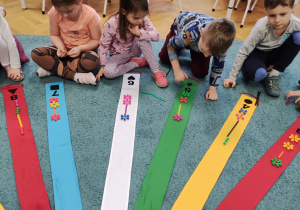 Dzieci układają rytmy na kolorowym wiatraku rozłożonym na dywanie