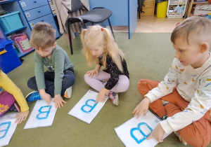 Hanie, Mateusz i Leon rysują palcami na wyklejonych wzorach litery "B" w rytmie piosenki "Bronisław"