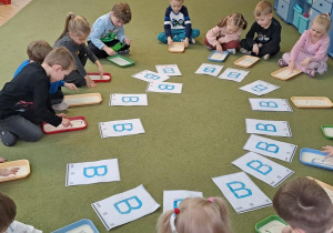 Dzieci piszą na kaszy litery "B" w rytmie piosenki "Bronisław"