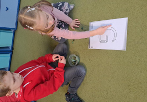 Lena i Janek układają literę "G" z zielonych guzików