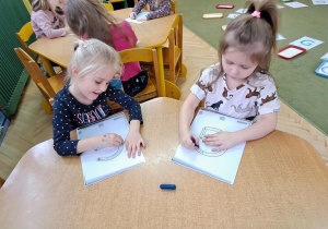 Nadia i Marysia piszą litery "G" na kartkach w rytmie piosenki "Grzegorz"