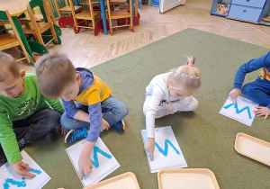 Janek, Mateusz, Nadia, Tymek kreślą palcami litery "W" na wyklejonych wzorach w rytmie piosenki "Weronika"