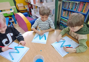 Stasio, Olaf, Filip piszą do piosenki "Weronika" litery "W" za pomocą pędzli namoczonych wodą z farbą