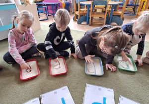 Olaf, Lena, Staś, Oliwia i Nadia rysują palcami litery "P" na tackach z kaszą do piosenki "Pola"
