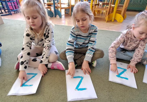 Oliwka, Remik i Lena kreślą palcami litery "Z" na wyklejonych wzorach do piosenki "Zuzanna"