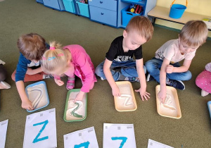 Dzieci rysują litery "Z" na kaszy do piosenki "Zuzanna"