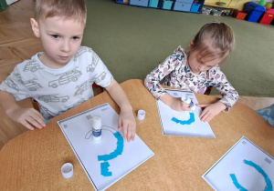 Antek i Klara wyklejają niebieską wydzieranką wzory litery "C"