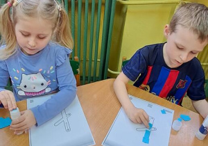 Oliwka i Janek wyklejają wzory litery "Ł" niebieską wydzieranką