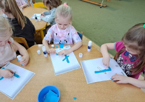 Hania, Nadia i Marysia wyklejają wzory litery "Ł" niebieską wydzieranką
