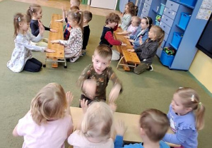 Dzieci wygrywają sylaby słów z piosenki "Łukasz", uderzając dłońmi o ławki