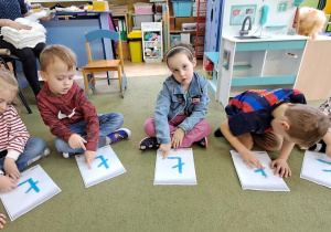 Dzieci "rysują" palcami litery "Ł" na wyklejonych wzorach do piosenki "Łukasz"