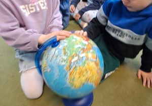 Gabrysia i Tymek oglądają globus, zwracając uwagę na ilość wody na naszej planecie