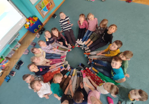 Dzieci siedzą w kole, mają założone kolorowe skarpetki symbolizujące niedopasowane chromosomy.