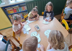 Puchatki przy żółtym stoliku kolorują sylwety dzieci przedstawiające przyjemne emocje