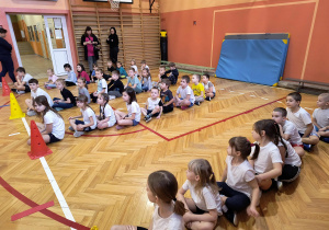 Dzieci podzielone na zespoły słuchają wskazówek