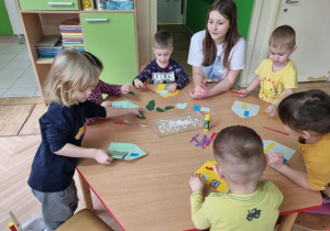 Dzieci przy stoliku tworzą kolorowe domki z kopert