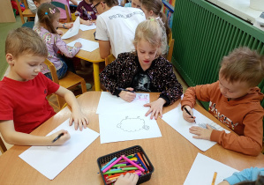 Dzieci przy zielonym stoliku rysują zwierzątka