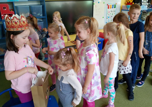 Dziewczynka częstuje swoich rówieśników urodzinowymi cukierkami