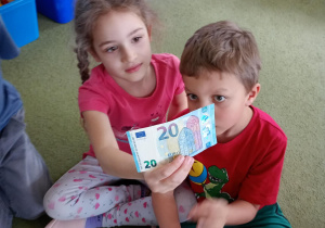 Chłopiec i dziewczynka oglądają banknot 20 euro