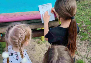 Dzieci z grupy Jeży podczas zabawy w ogrodzie, wypełniają listę