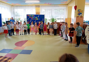 Puchatki stoją w półkolu i śpiewają piosenkę.