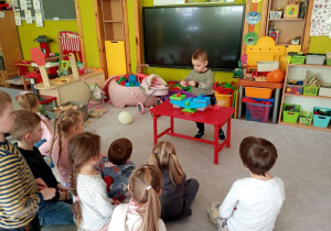 Chłopiec kładzie na wagę odważniki i stara się, aby ichwaga była równa