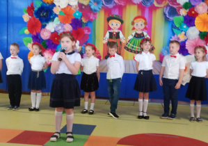 Hania recytuje wiersz, w tle stoją dzieic ubrane na biało- granatowo