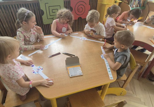 dzieci przy żółtym stoliku kolorują swoje opaski