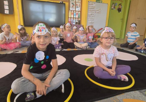 dzieci siedzą w kółkach i słuchają piosenki o kropkach