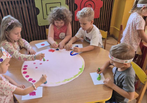 dzieci wspólnie tworzą obraz z kropek robionych farbami