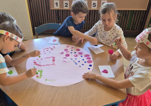 dzieci wspólnie tworzą obraz z kropek robionych farbami