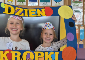 dziewczynki pozują do zdjęcia w ramce z kropek