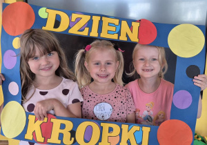 dziewczynki pozują do zdjęcia w ramce z kropek