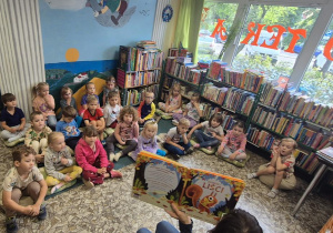 dzieci słuchają książkę czytaną przez panią z biblioteki
