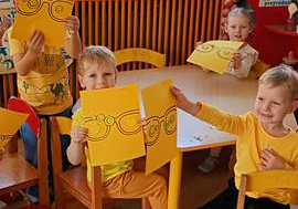 Dzieci ozdabiają magiczne żółte okulary przy żółtym stoliku