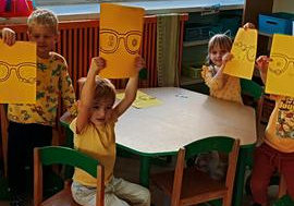 Dzieci ozdabiają magiczne okulary przy zielonym stoliku