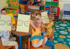 Dzieci ozdabiają magiczne okulary przy niebieskkim stoliku