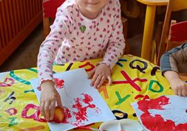 Marysia ozdabia dzrewo stemplami z jabłek