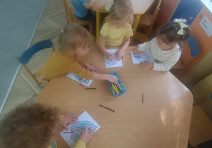Maluszki kolorują listki przy stoliku