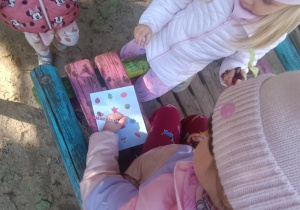 Dziewczynki wypełniają kartę zaobserwowanych skarbów jesieni