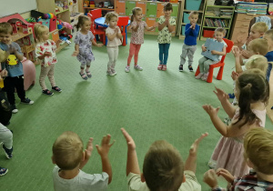 Dzieci stoją w kole i śpiewają Oliwce sto lat