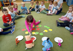 Dziewczynka rozdziela sylwety owoców według instrukcji nauczycielki