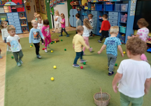 Dzieci spacerują po sali między piłkami symbolizującymi owoce