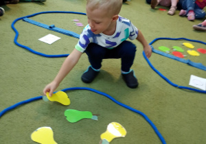 Chłopiec przydziela do koszyka ze schematem gruszki właściwy owoc