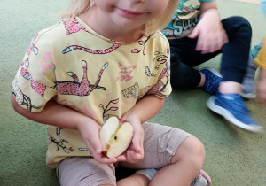 Dziewczynka ogląda połówkę jabłka