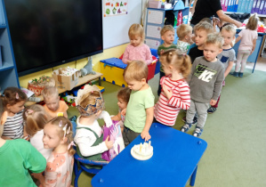 Dziewczynka częstuje dzieci urodzinowymi żelkami